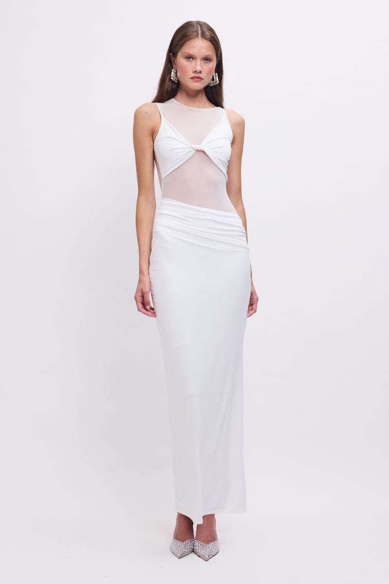 A woman wearing a white sleeveless maxi dress with a twist front detail and side slit.