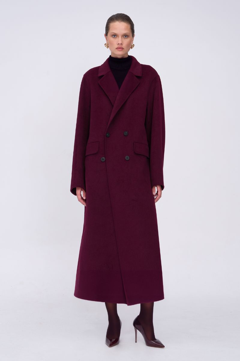 Woman wearing a long burgundy coat on a white background