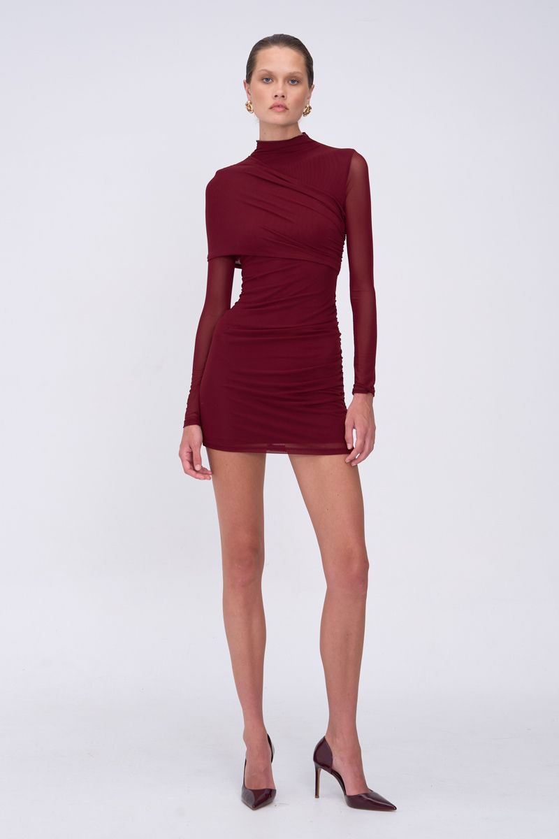 Model wearing a burgundy dress with long sleeves on a white background