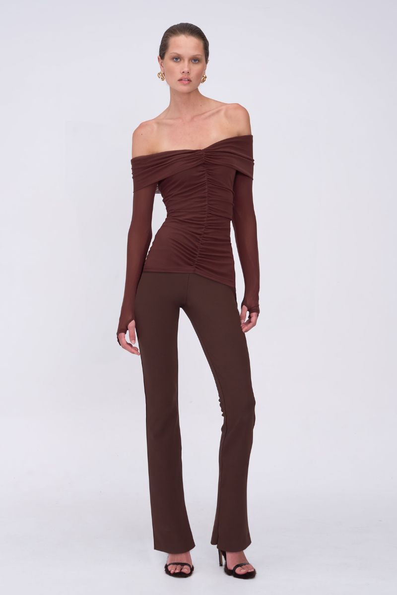 Woman wearing a brown off-shoulder top and pants on a white background