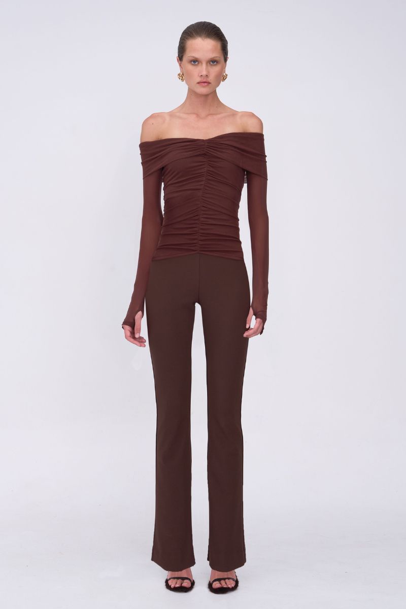 Woman wearing a brown off-shoulder top and pants on a white background