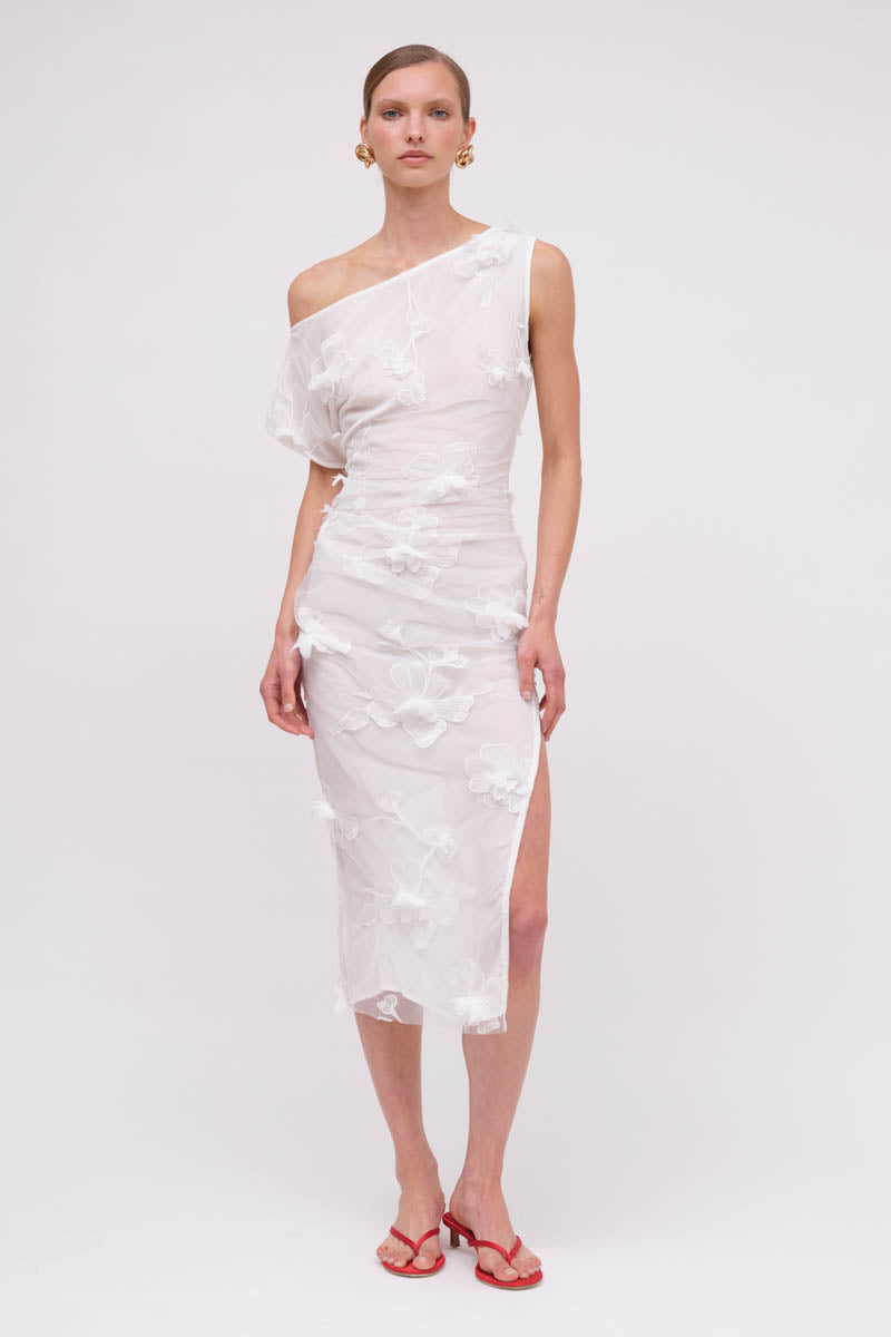 Woman wearing a white one-shoulder dress on a plain background