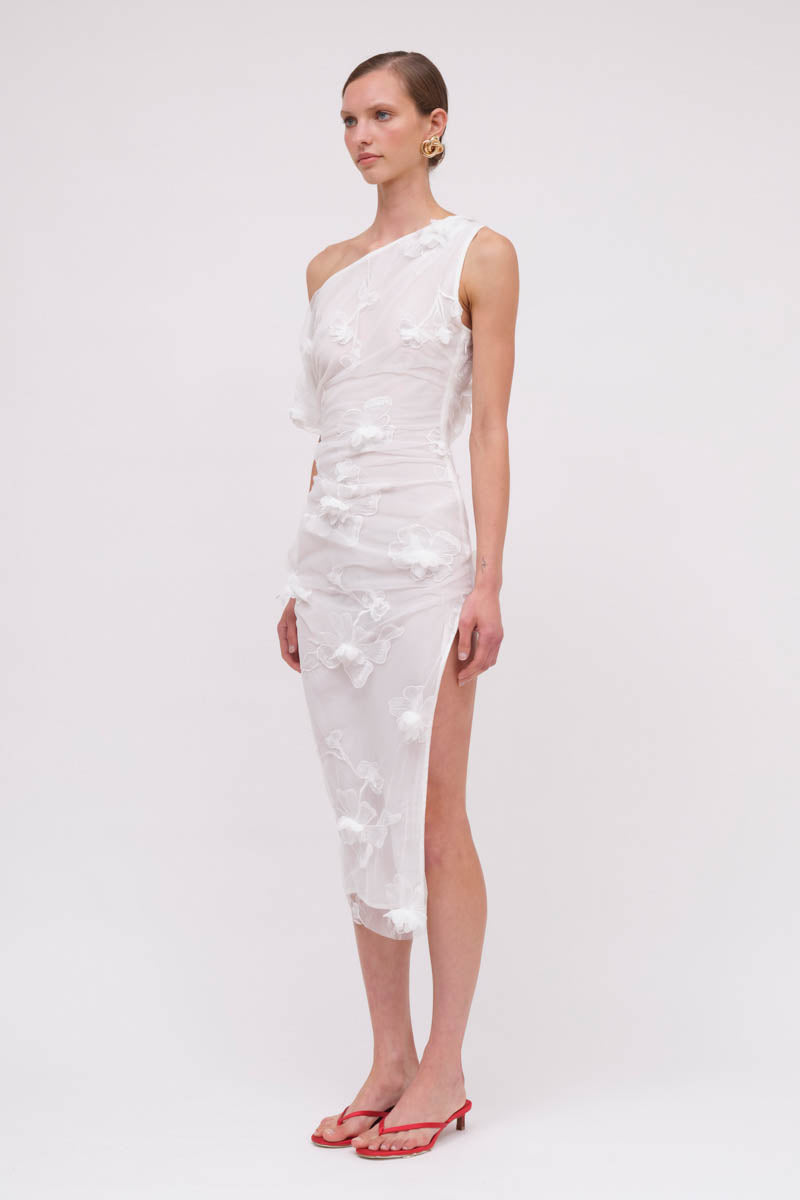 Woman wearing a white one-shoulder dress with floral patterns on a white background
