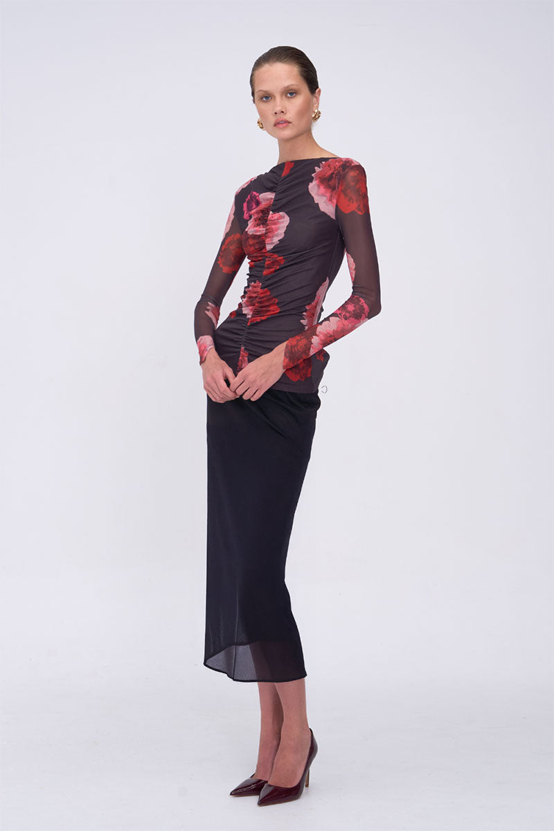 Woman wearing a black top with red floral patterns on a white background