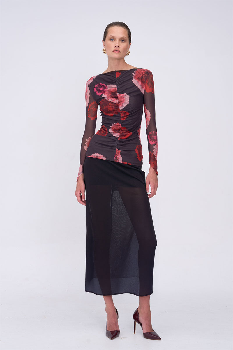 Model wearing a black top with red floral patterns on a white background