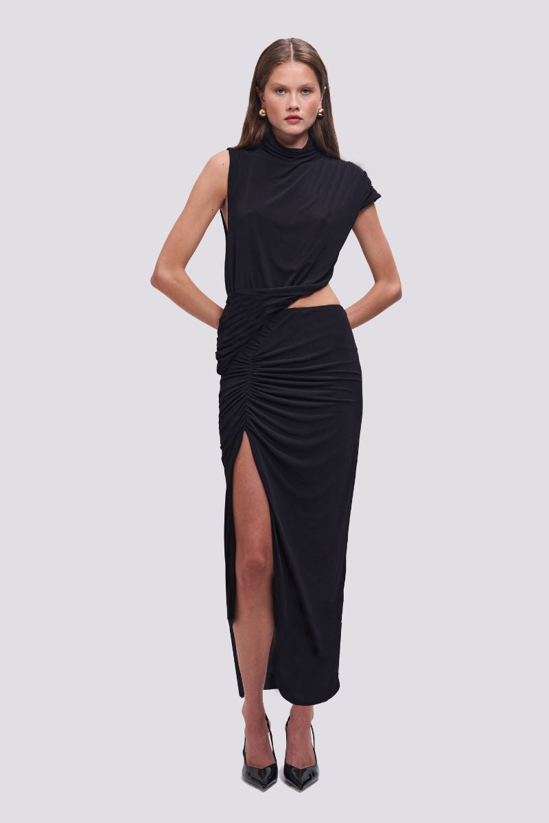 Woman wearing a black dress with a slit on a light gray background