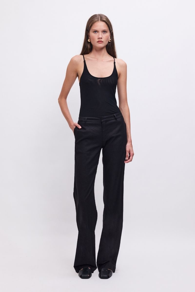 Woman wearing a black tank top and black pants on a white background