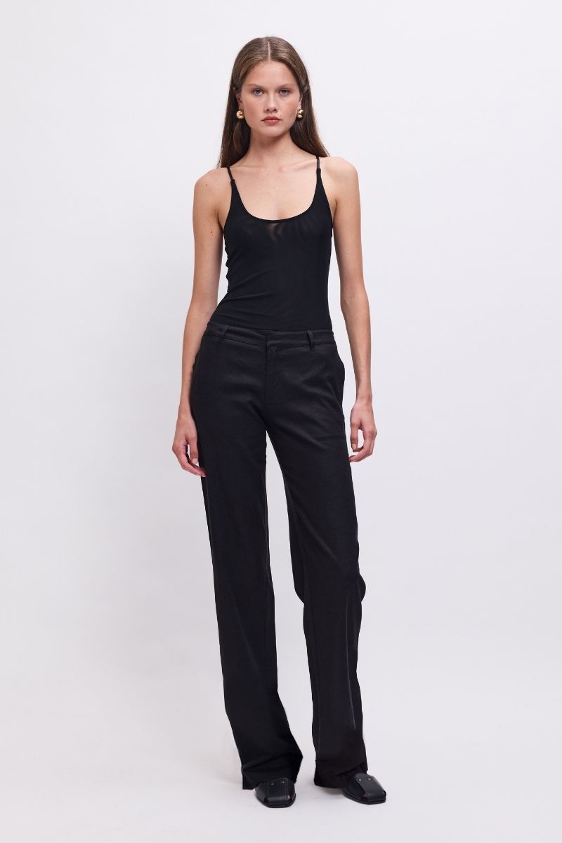 Woman wearing a black sleeveless top and black pants on a white background