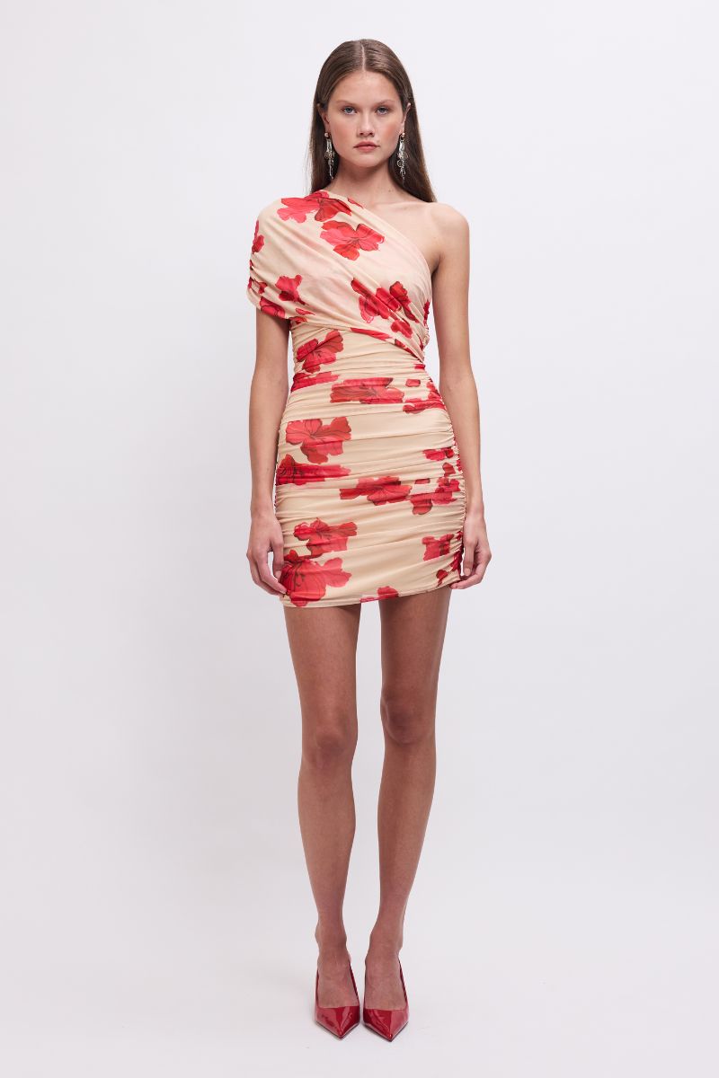 Woman wearing a one-shoulder dress with red floral pattern on a white background