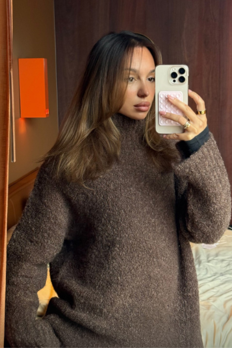 Woman wearing a brown sweater indoors.